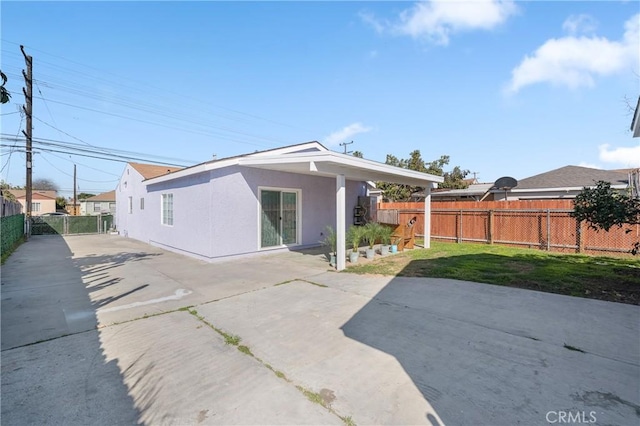 rear view of house featuring stucco siding, a lawn, a patio, and fence