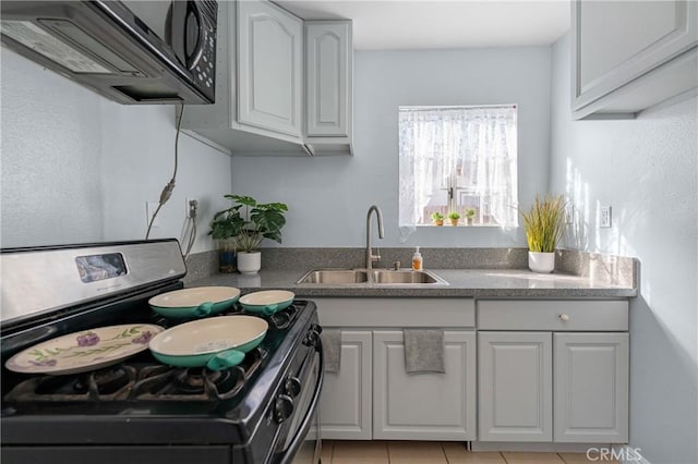 kitchen with stainless steel range with gas stovetop, white cabinets, black microwave, and a sink