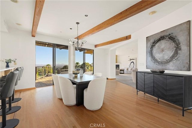 dining area featuring beamed ceiling, baseboards, an inviting chandelier, and light wood finished floors