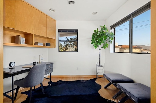 office featuring plenty of natural light, wood finished floors, visible vents, and baseboards