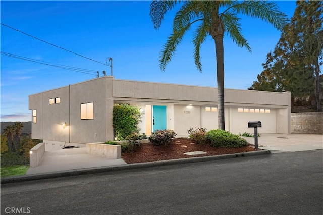 view of front facade featuring concrete driveway, an attached garage, and stucco siding