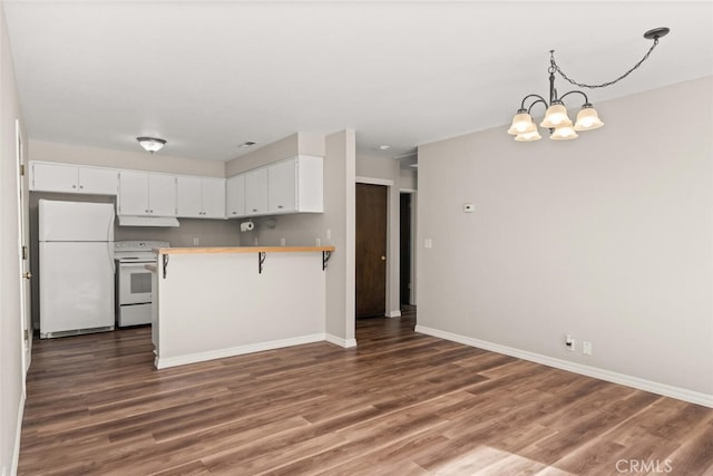 kitchen with under cabinet range hood, wood finished floors, white appliances, a peninsula, and an inviting chandelier