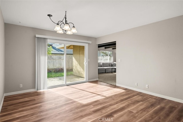 unfurnished room with a chandelier, baseboards, and wood finished floors