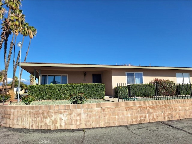 ranch-style house featuring stucco siding and fence