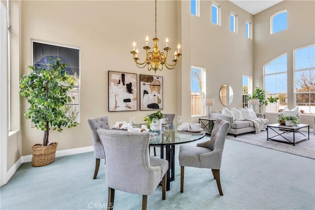 dining space featuring carpet, baseboards, a towering ceiling, and a chandelier