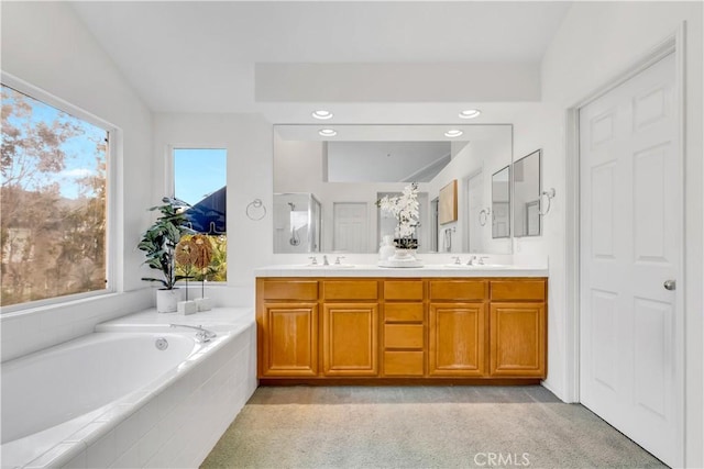 bathroom featuring a sink, a bath, and double vanity