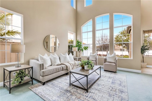 carpeted living area featuring a high ceiling and baseboards