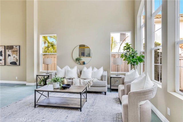 carpeted living room featuring a high ceiling and baseboards