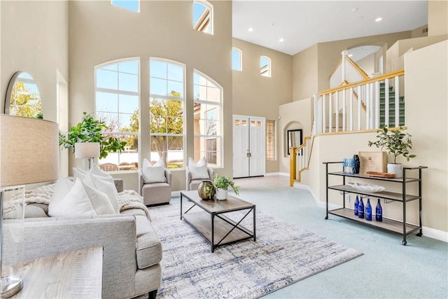 living room with baseboards, recessed lighting, stairs, a towering ceiling, and carpet flooring