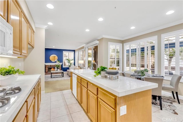 kitchen featuring crown molding, tile counters, open floor plan, white appliances, and a sink