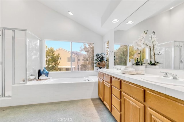 bathroom with a bath, vaulted ceiling, a stall shower, and a sink