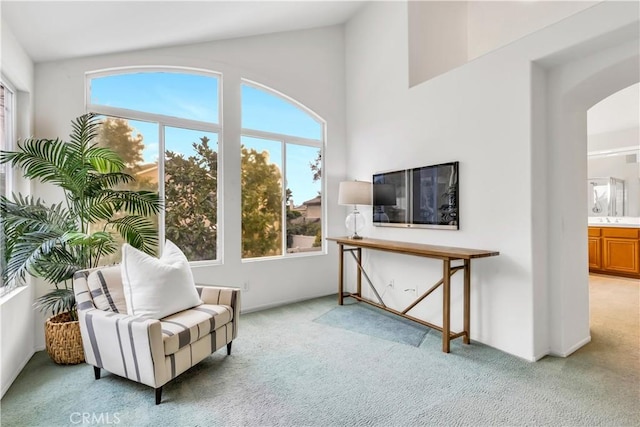 sitting room featuring light carpet, arched walkways, lofted ceiling, and a wealth of natural light