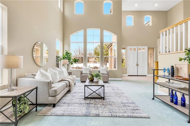 carpeted living area with recessed lighting, baseboards, and a towering ceiling