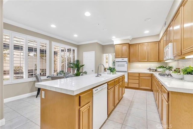 kitchen featuring tile countertops, ornamental molding, light tile patterned flooring, white appliances, and a sink