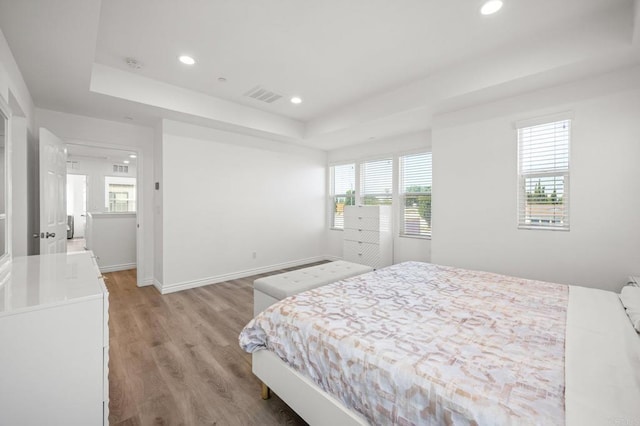 bedroom featuring visible vents, baseboards, a tray ceiling, light wood-style flooring, and recessed lighting