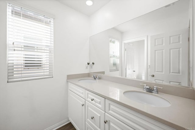 full bath with double vanity, baseboards, and a sink