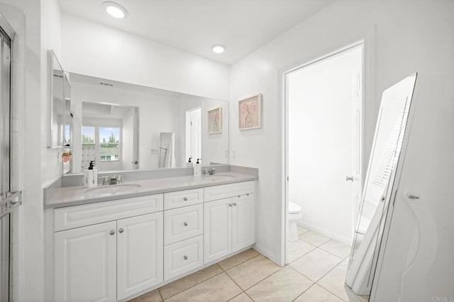 bathroom featuring a sink, toilet, double vanity, and tile patterned flooring