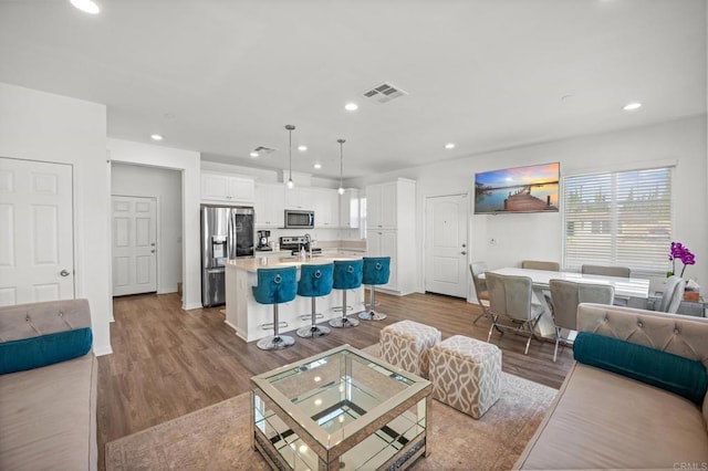 living area with visible vents, recessed lighting, baseboards, and wood finished floors