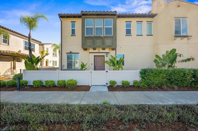 view of front of home with a fenced front yard, stucco siding, and a gate