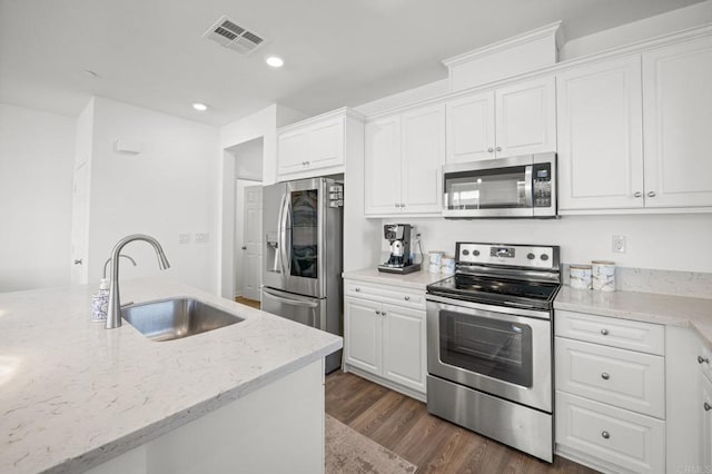 kitchen featuring visible vents, a sink, stainless steel appliances, white cabinets, and dark wood-style flooring