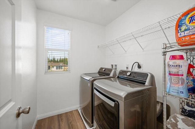 washroom featuring baseboards, wood finished floors, laundry area, and washer and clothes dryer