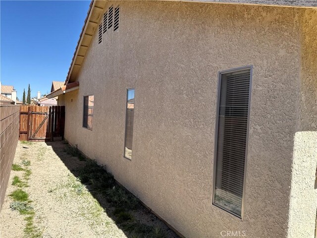 view of side of property featuring a gate, stucco siding, and fence