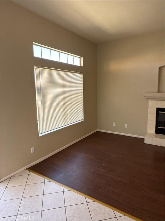 unfurnished living room featuring wood finished floors, a fireplace, and baseboards