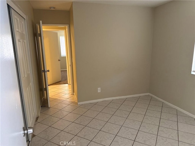 spare room featuring light tile patterned flooring and baseboards