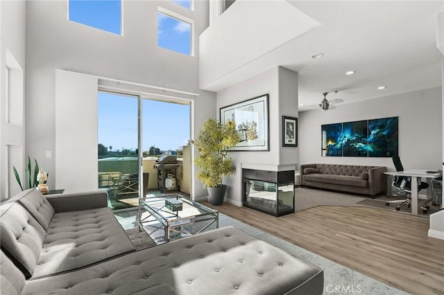 living area featuring recessed lighting, wood finished floors, a multi sided fireplace, and a wealth of natural light