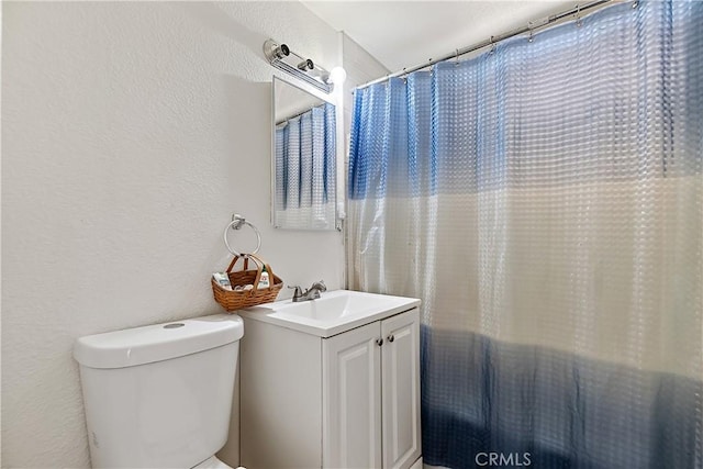 bathroom with toilet, vanity, a shower with shower curtain, and a textured wall