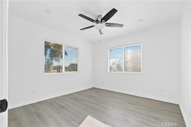 empty room with plenty of natural light, baseboards, and wood finished floors