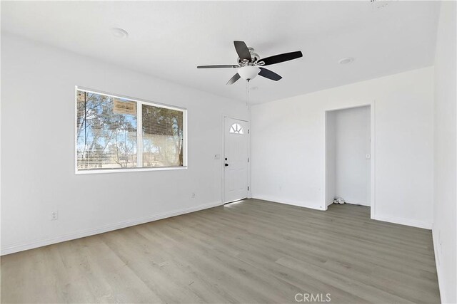 empty room featuring ceiling fan, baseboards, and wood finished floors