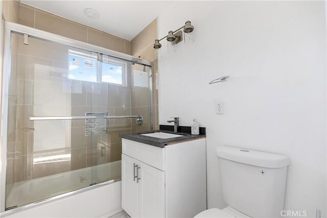 full bathroom featuring combined bath / shower with glass door, toilet, and vanity