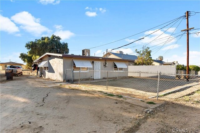 back of property with a fenced front yard and stucco siding