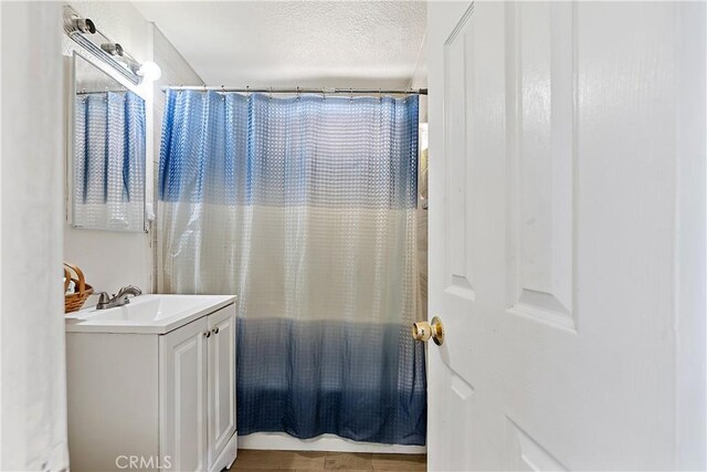 bathroom with a shower with curtain, a textured ceiling, and vanity