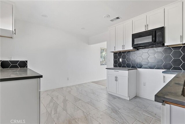 kitchen with visible vents, marble finish floor, dark countertops, white cabinetry, and black microwave