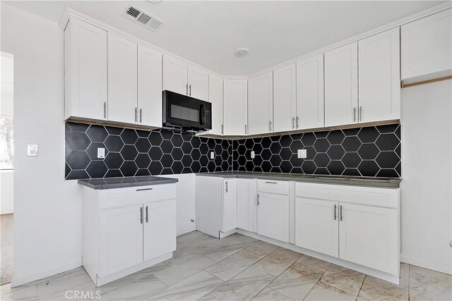 kitchen featuring dark countertops, visible vents, marble finish floor, and black microwave