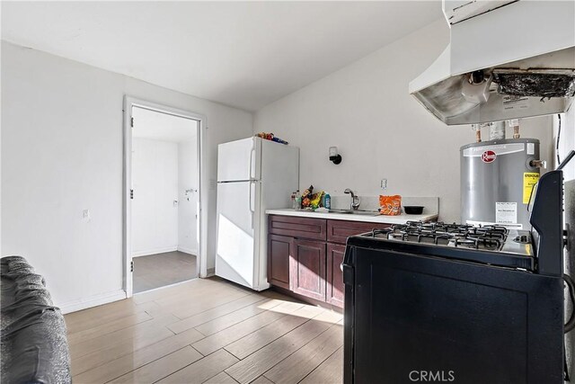 kitchen featuring freestanding refrigerator, light countertops, black gas range, light wood-style floors, and under cabinet range hood