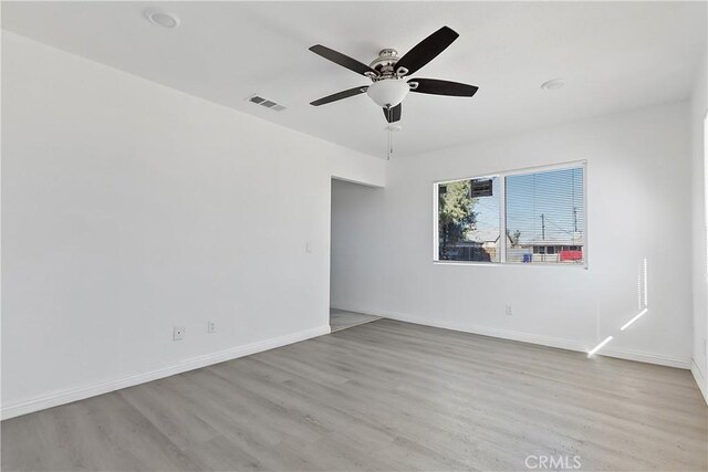 unfurnished room featuring ceiling fan, visible vents, baseboards, and wood finished floors