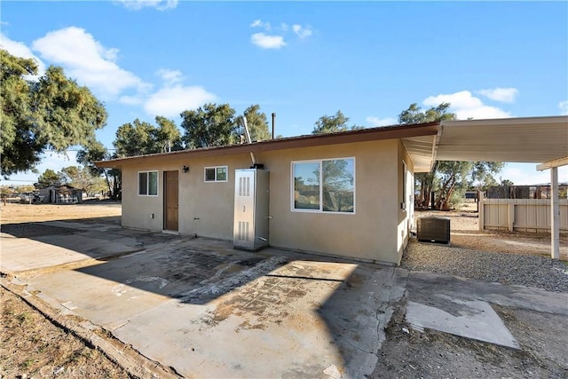 rear view of house with a patio area, fence, central AC, and stucco siding