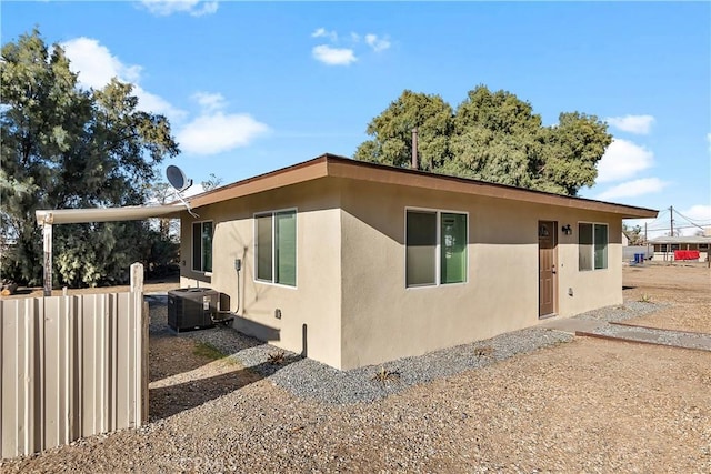 view of property exterior featuring cooling unit, fence, and stucco siding