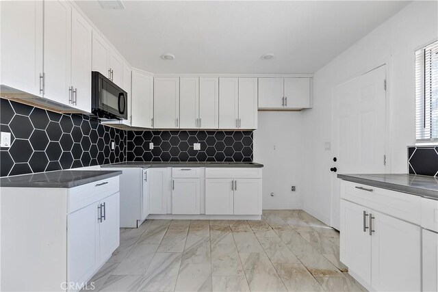 kitchen featuring dark countertops, marble finish floor, white cabinets, and black microwave