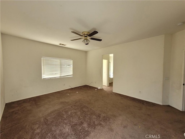 carpeted spare room featuring visible vents and ceiling fan