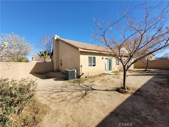 rear view of property with a tiled roof, central air condition unit, a fenced backyard, and stucco siding