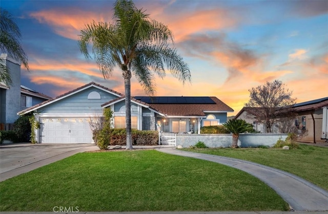 view of front of property featuring solar panels, a fenced front yard, a tiled roof, driveway, and an attached garage