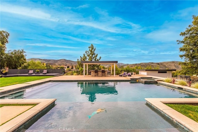 view of swimming pool featuring a mountain view, a pool with connected hot tub, and a patio