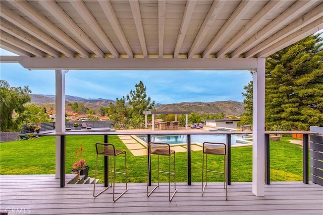 deck with a yard, an outdoor pool, and a mountain view