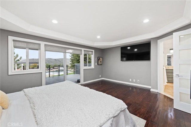 bedroom with access to exterior, dark wood-type flooring, baseboards, a tray ceiling, and recessed lighting