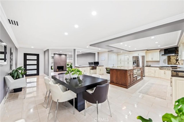 dining area with light tile patterned floors, a large fireplace, ornamental molding, and recessed lighting