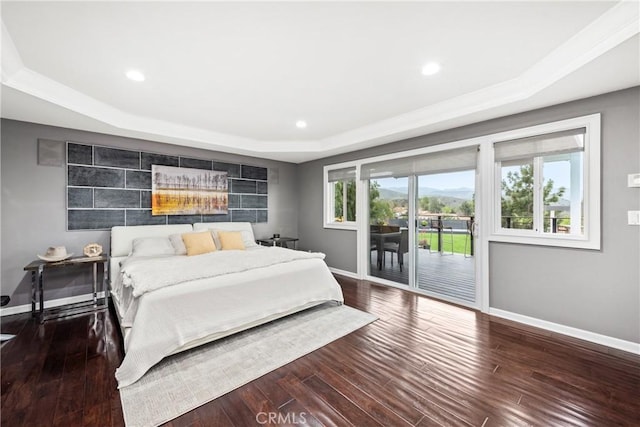 bedroom with wood finished floors, baseboards, recessed lighting, a raised ceiling, and access to outside